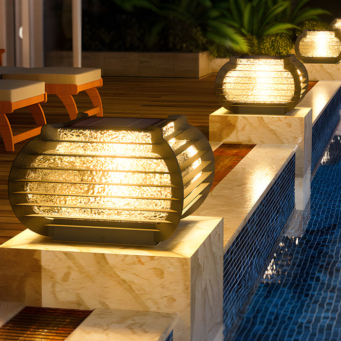 Warm glowing lantern pillar lights placed beside a swimming pool, creating a relaxing and upscale outdoor ambiance.