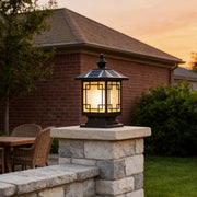 Lantern pillar lights installed on stone columns beside a residential patio at sunset.