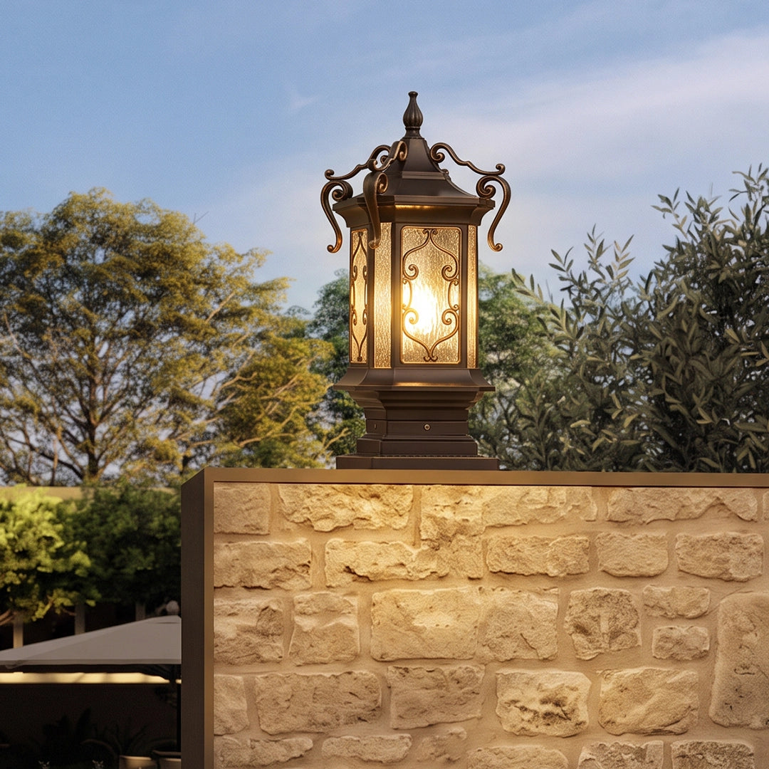 Lantern pillar lights on a stone garden wall with an antique bronze finish and decorative seeded glass panels.
