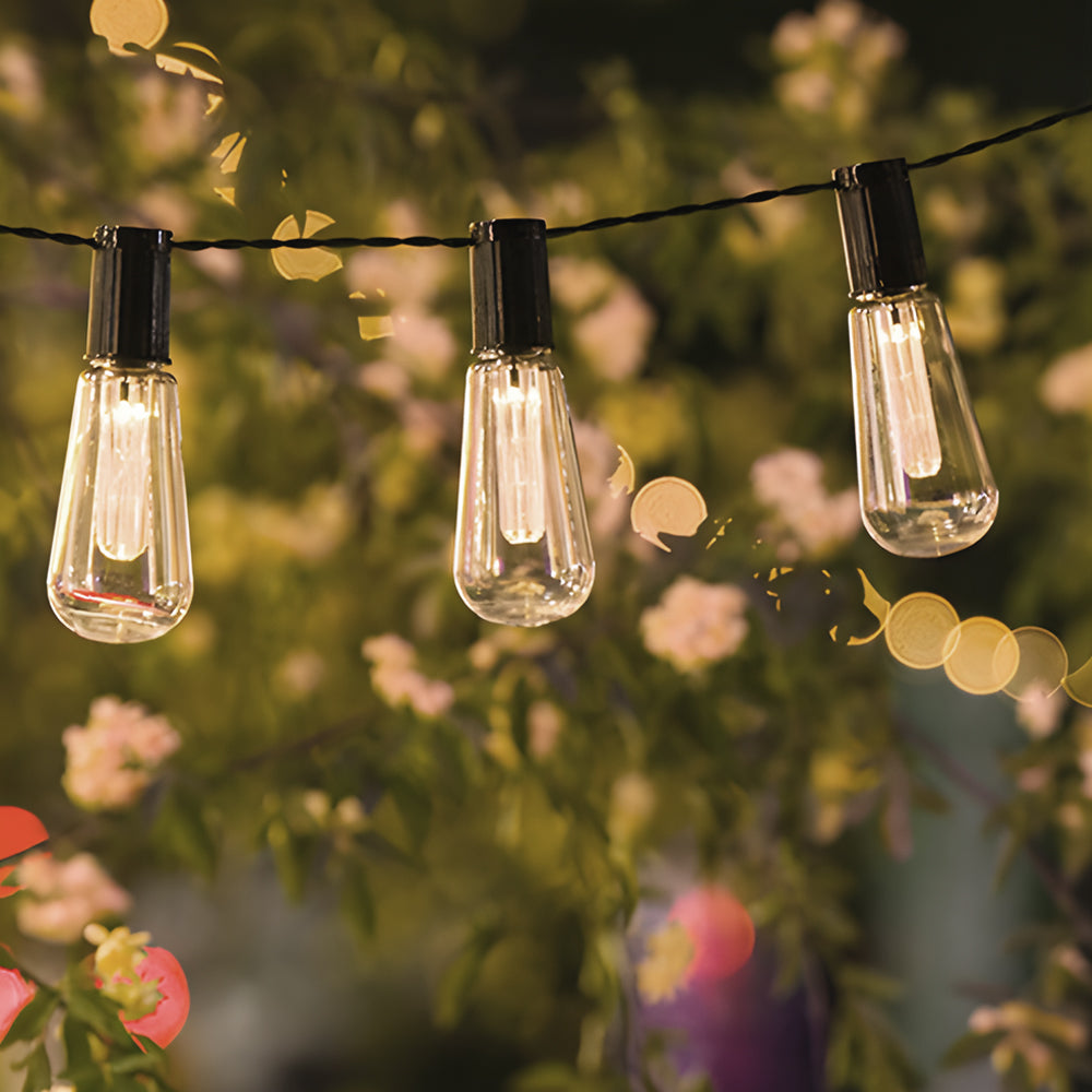 Decorative solar camping string lights with lantern-style bulbs illuminating garden party setting with beautiful bokeh background