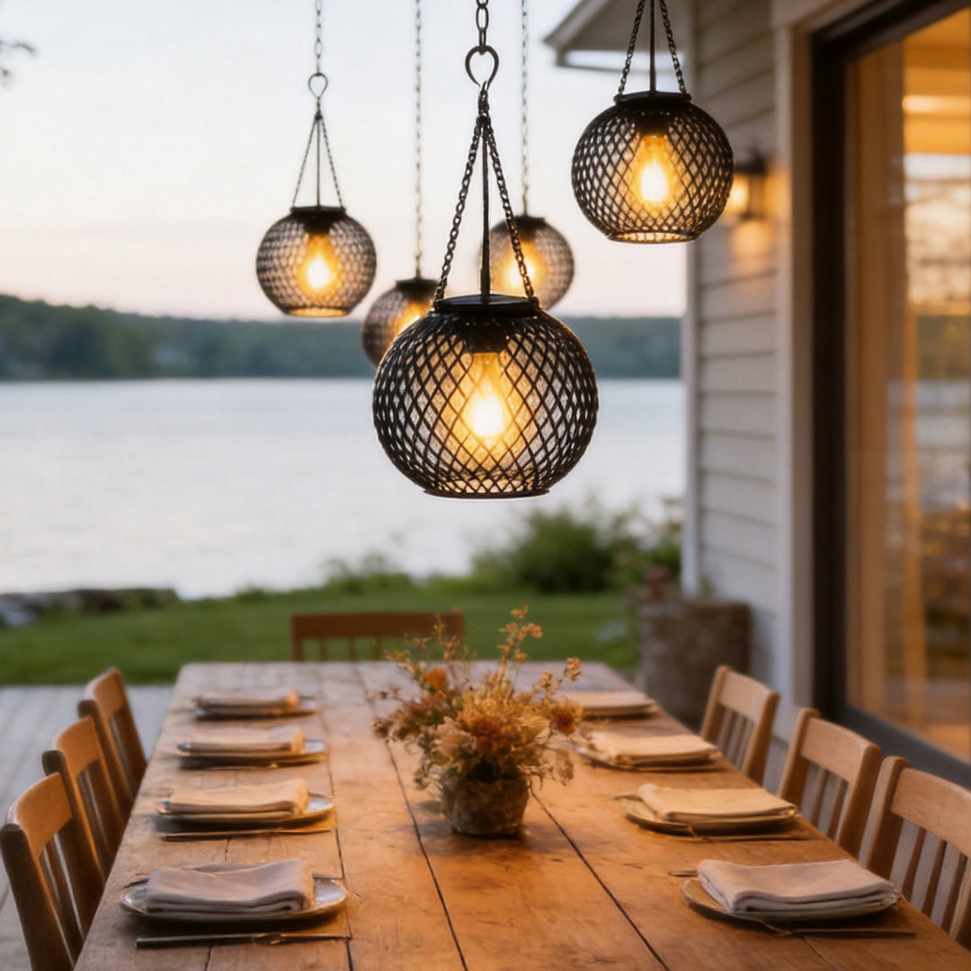 Lantern Style Outdoor Lights hanging over a rustic wooden dining table on a patio near water.