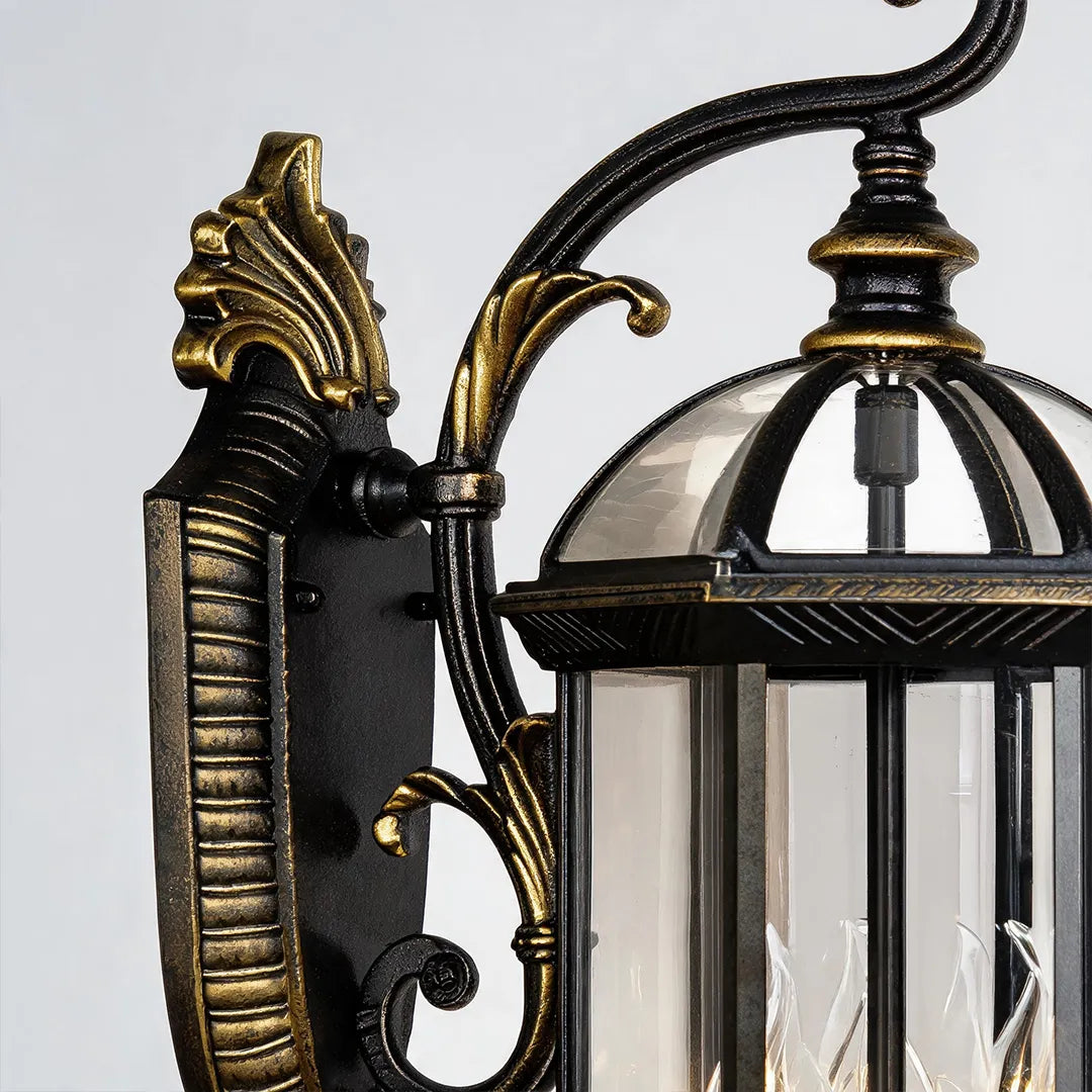 Lantern style outdoor wall light close-up highlighting the black and gold metal frame, glass dome top, and classic detailing.