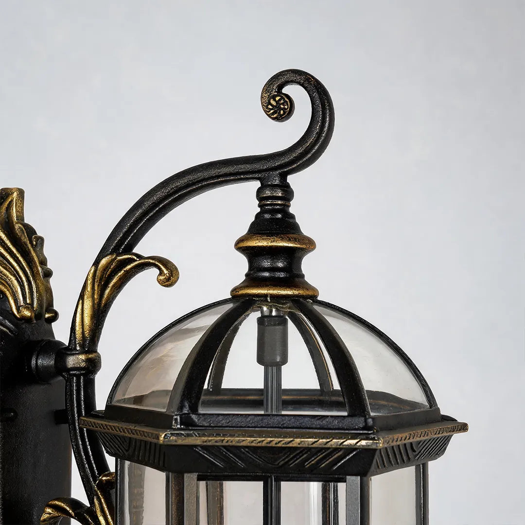 Lantern style outdoor wall light detail showing the decorative curved arm, vintage backplate, and glass lantern top.