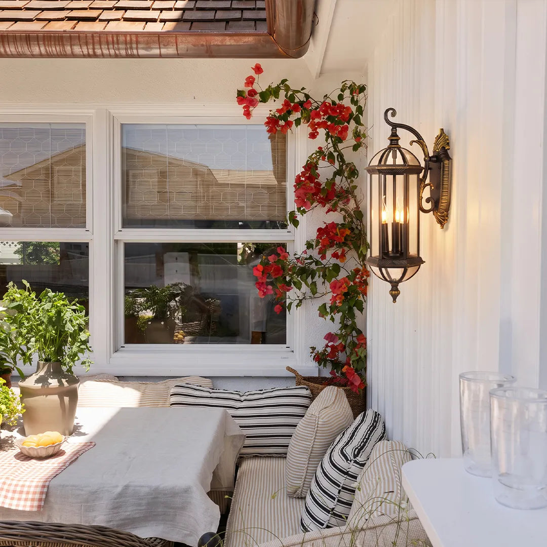 Lantern style outdoor wall lights installed beside a covered patio dining area, adding warm ambient lighting to the exterior wall.