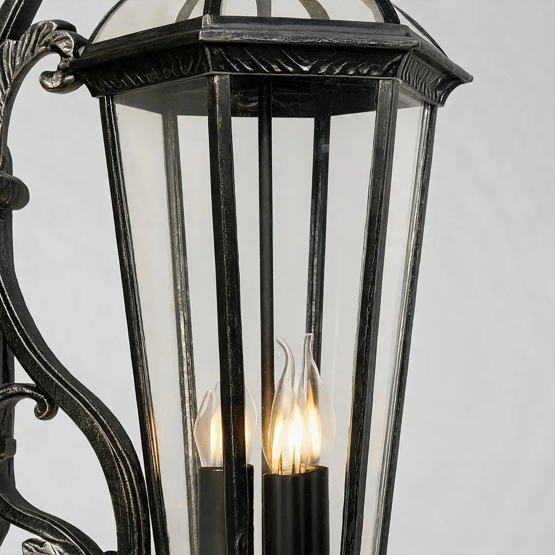 Lantern style wall sconce detail showing the black metal frame, clear glass enclosure, and candle-style light bulbs.
