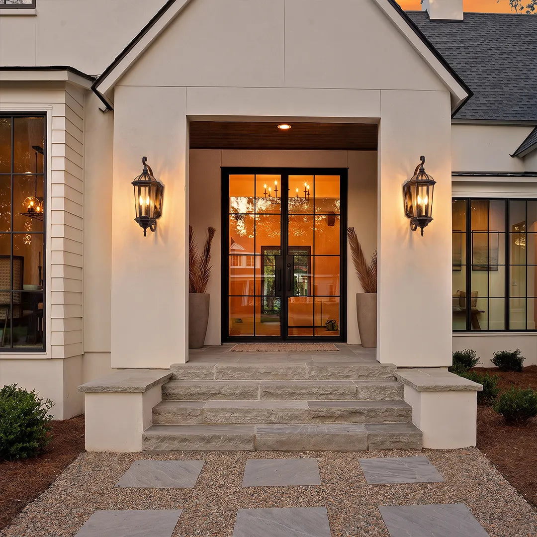 Lantern style wall sconces flanking a front door entrance, adding symmetrical outdoor lighting to the covered porch.