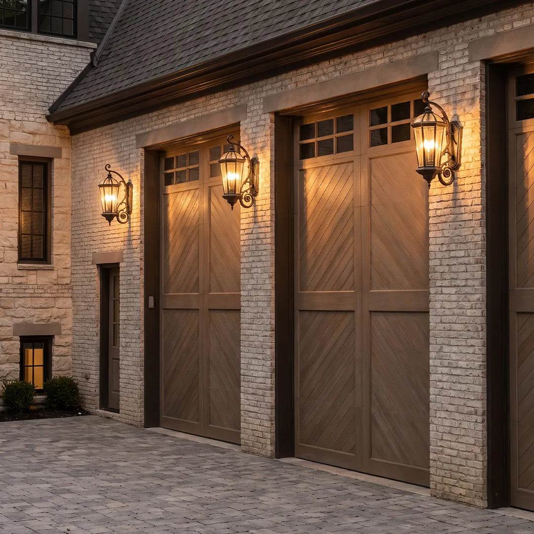 Lantern style wall sconces installed on a brick garage exterior, bringing warm traditional lighting to carriage-style doors.