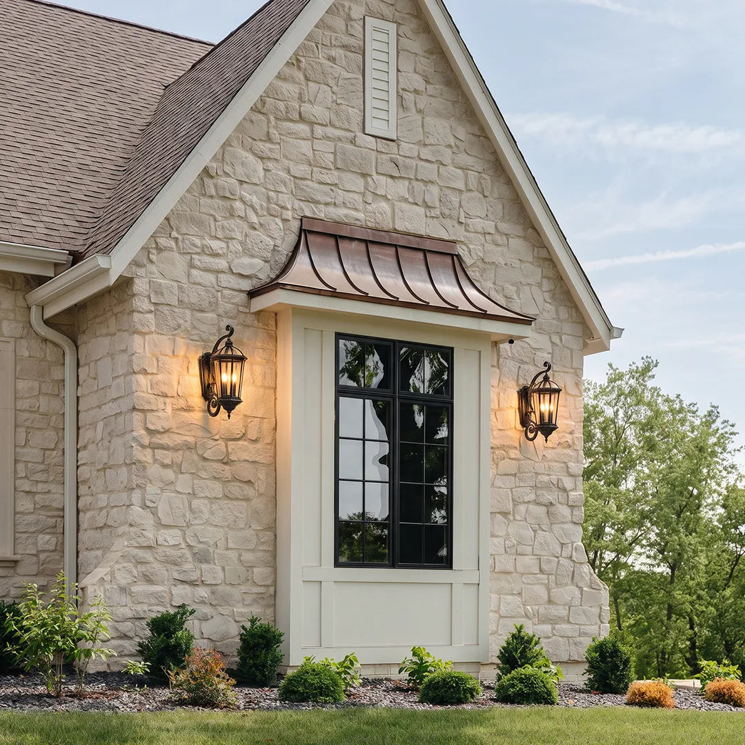 Lantern style wall sconces mounted on a stone house facade, providing elegant exterior lighting beside the front entry.