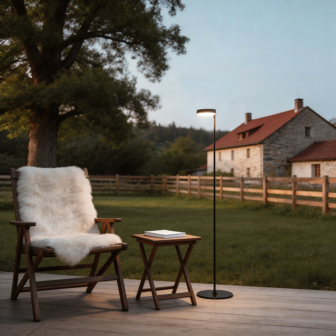 Elegant large black outdoor pillar light illuminating a cozy garden patio with stone pillars and wicker furniture.