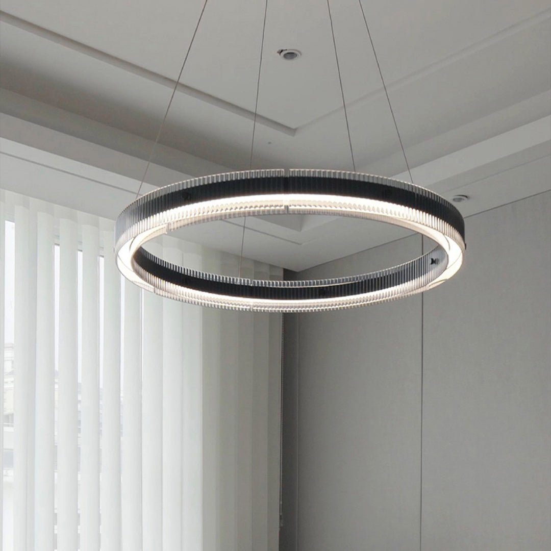 Large black round pendant light suspended in spacious modern interior with concrete walls