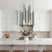 Large black staircase chandelier staggered over a modern white marble kitchen island surfaces.