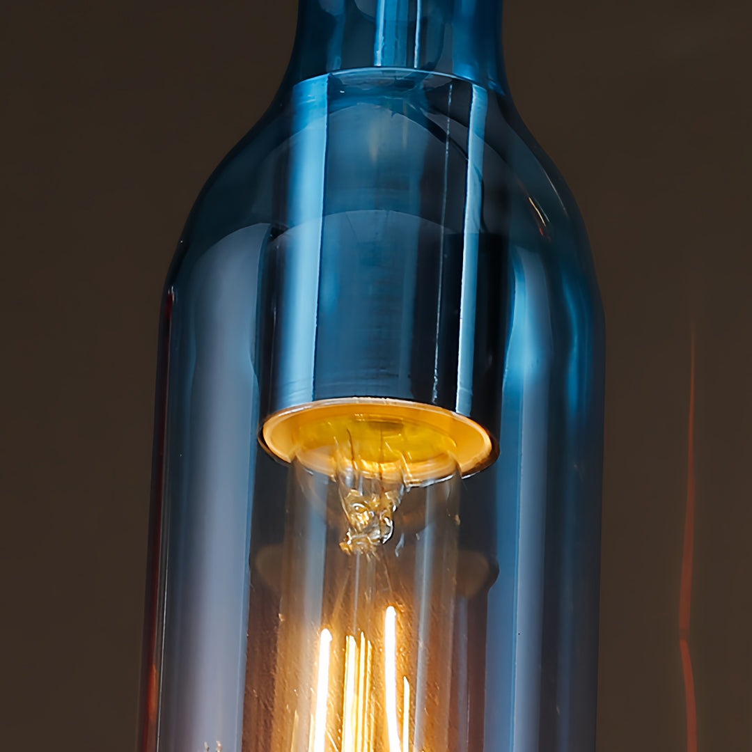 Large blue wine bottle pendant light with golden amber interior glow against dark background
