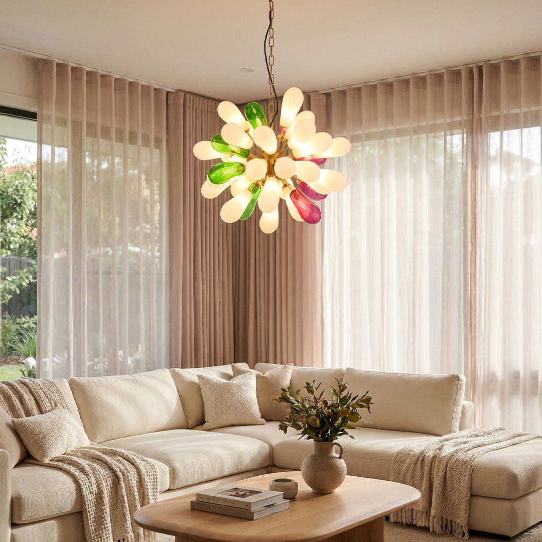 Contemporary large chandelier with multi-color glass bulbs hanging above a cozy sofa in a sunlit lounge.