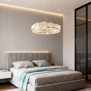 Large crystal chandeliers illuminating contemporary bedroom with tufted gray bed and textured wall creating elegant ambiance