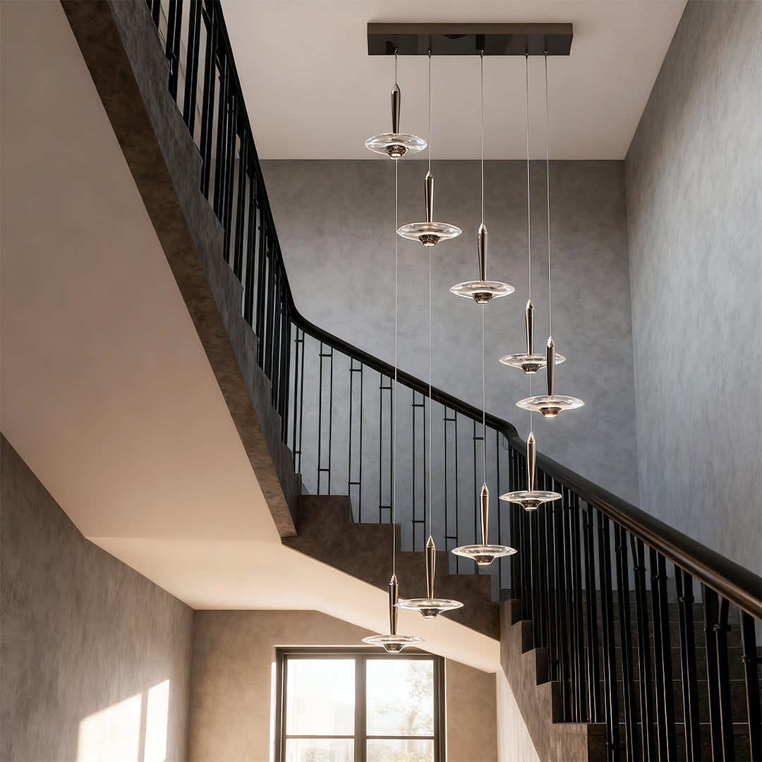 Large crystal pendant light cascading along curved staircase in elegant entryway with black metal railings