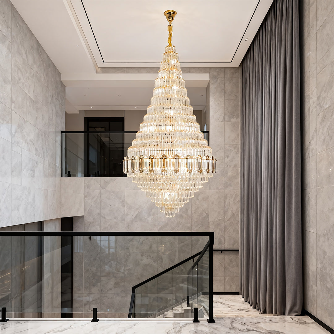 Large gold chandelier creating dramatic focal point in contemporary grey entrance hall with black accents.