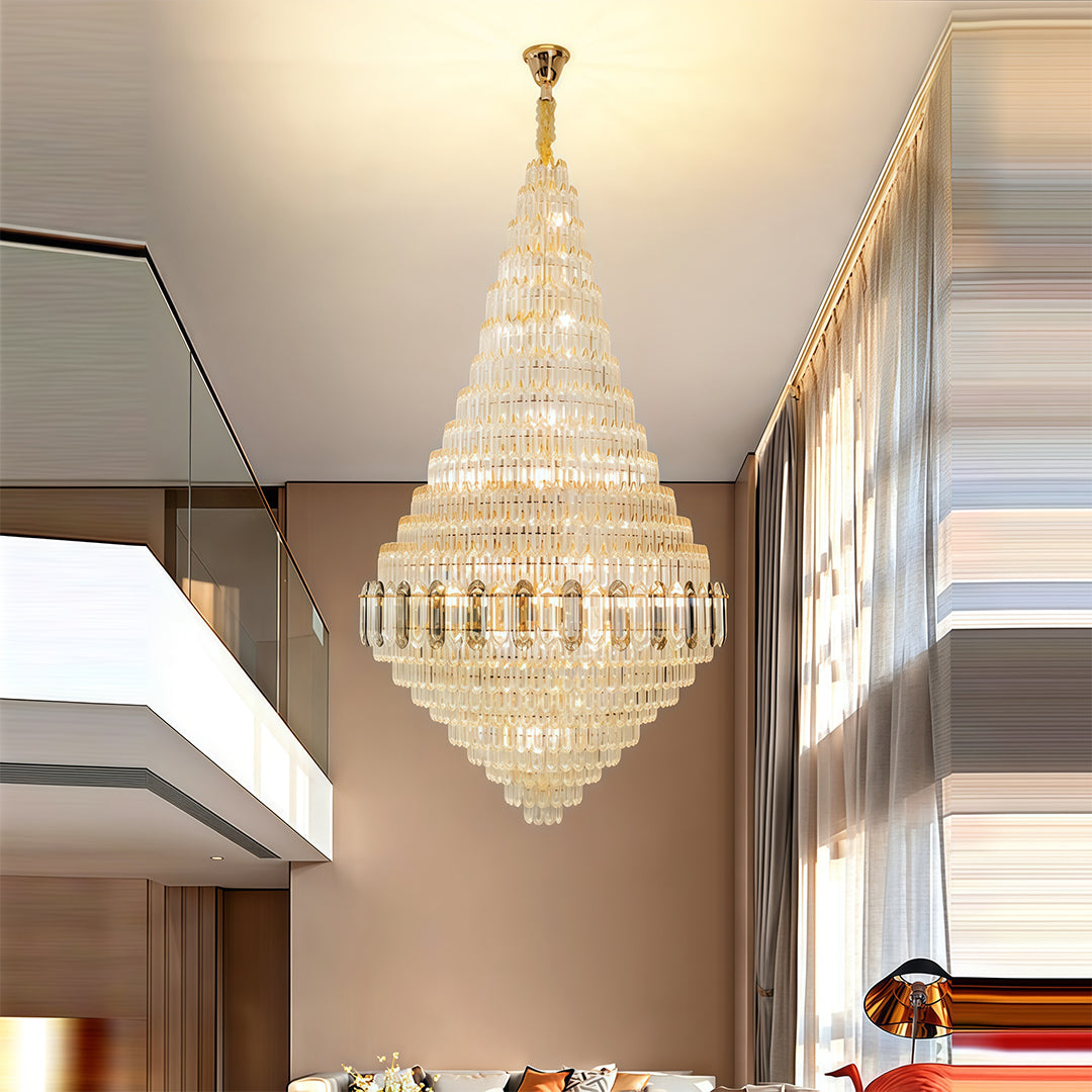 Large gold chandelier hanging in warm-toned hallway with cream walls and architectural detailing.