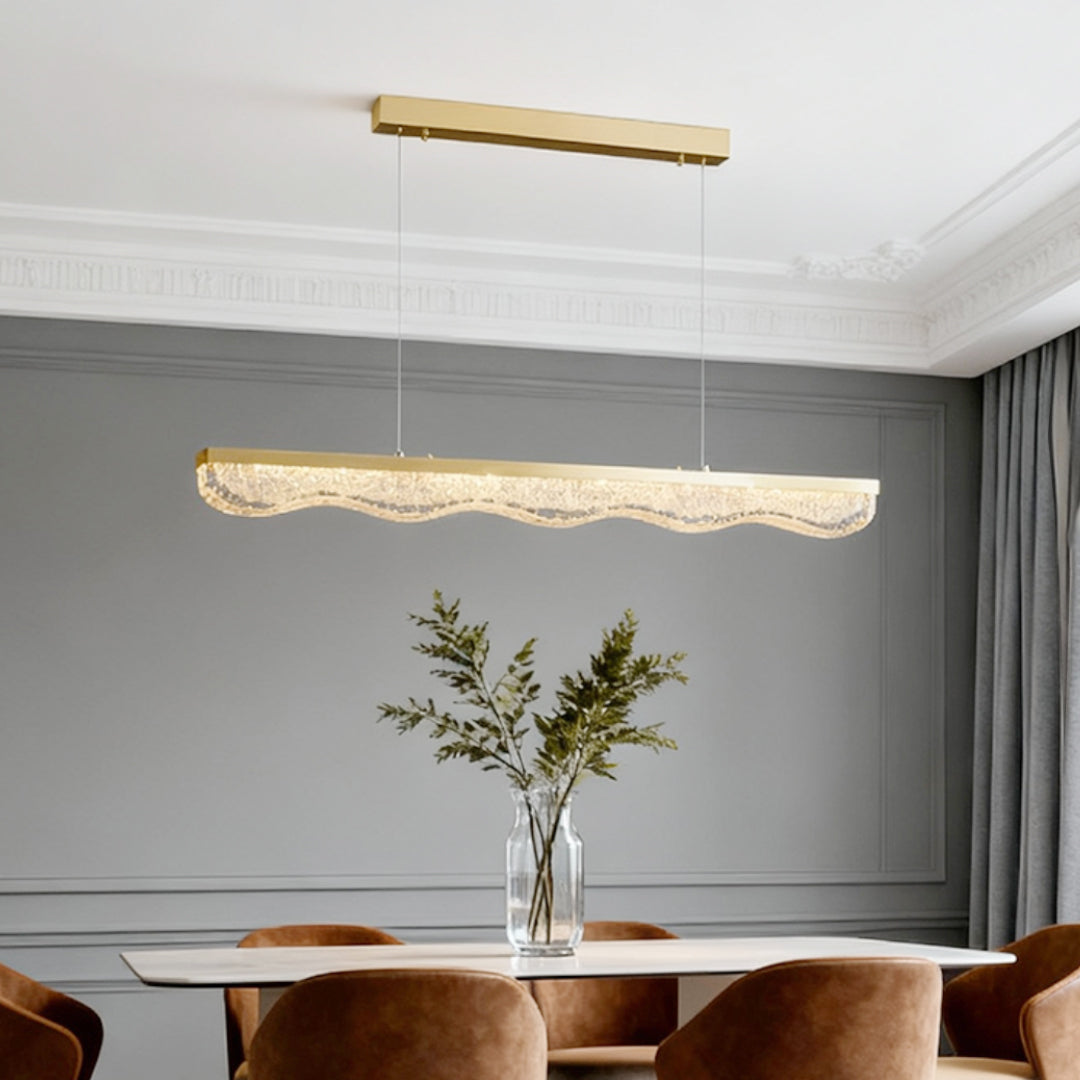 Large gold pendant light creating warm ambiance over brown velvet chairs in grey modern dining space.