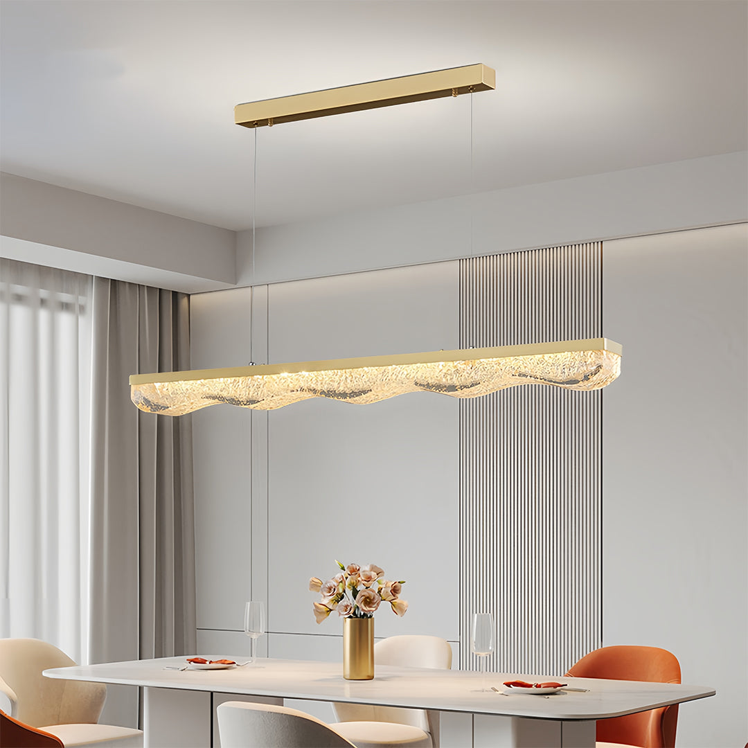 Large gold pendant light illuminating contemporary dining room with white table and orange accent chairs.