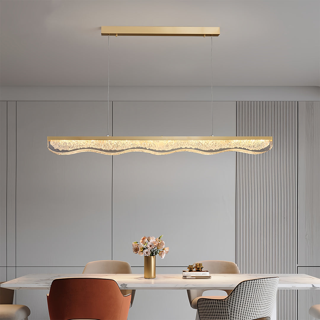 Large gold pendant light brightening minimalist dining area with rust-colored seating and grey walls.
