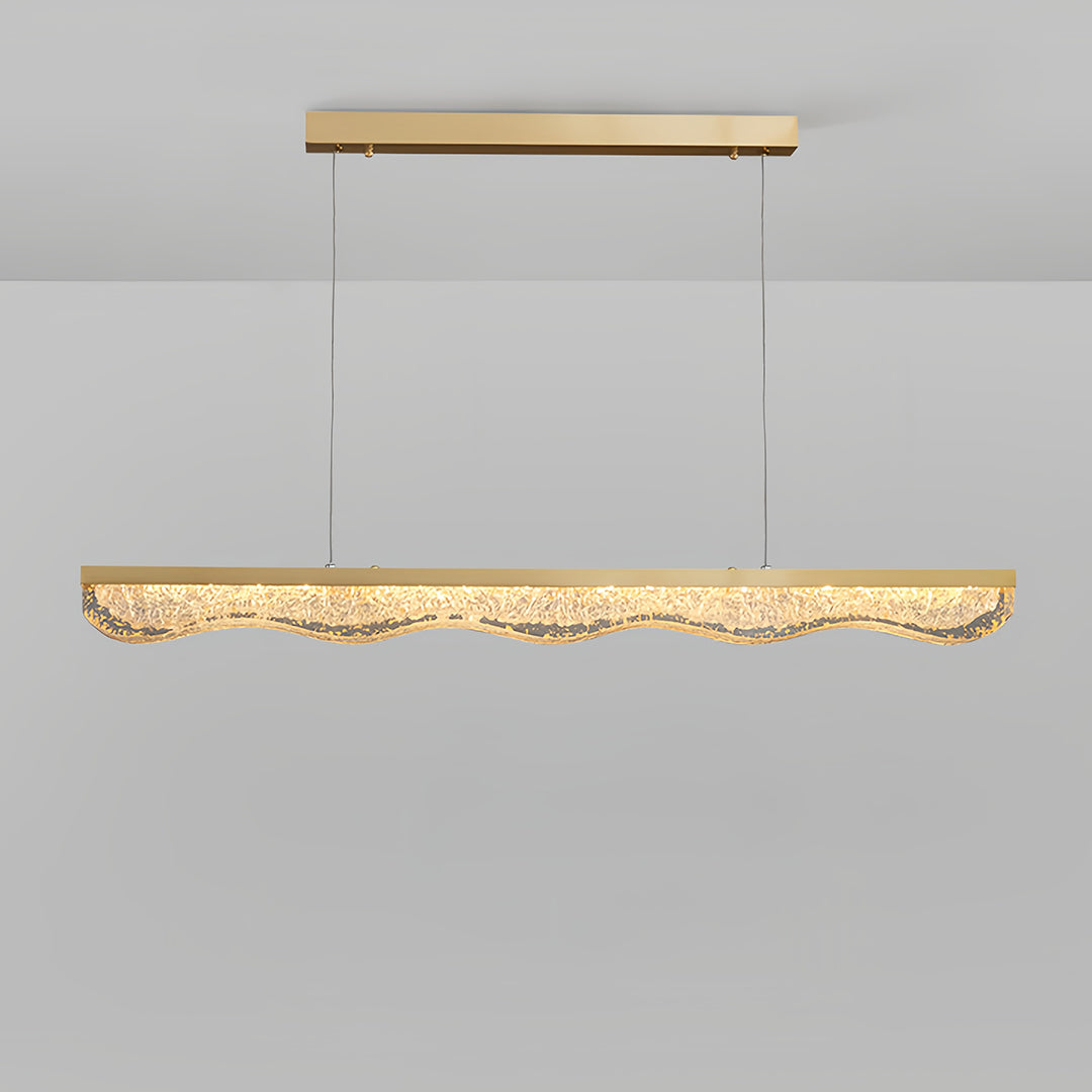 Large gold pendant light with sculptural glass displayed on neutral background showing warm LED glow.