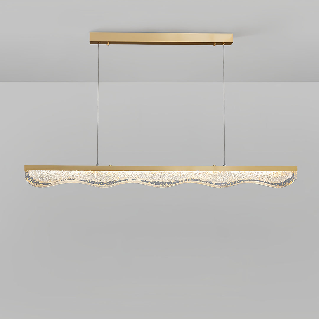 Large gold pendant light demonstrating suspended installation with long cables on grey surface.