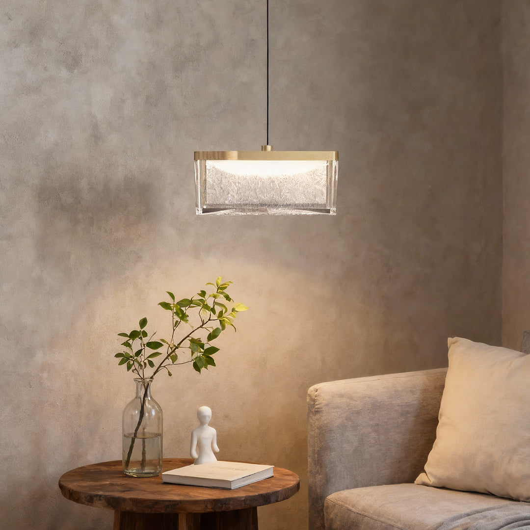 Large metal pendant lights creating ambient glow on concrete-style wall beside modern chair and round side table