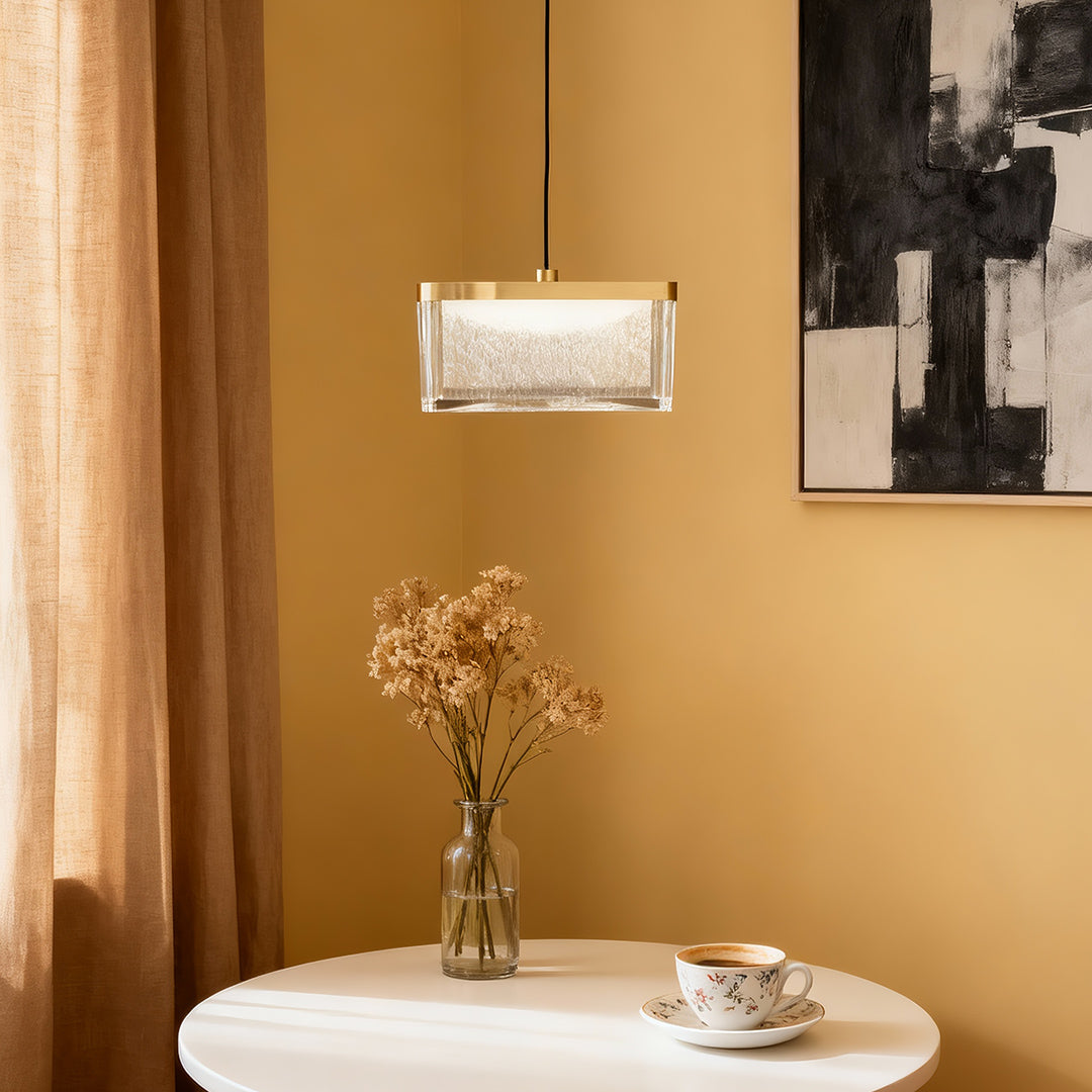 Large metal pendant lights above white round table with golden curtains and botanical arrangement in warm interior