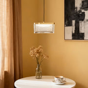 Large metal pendant lights above white round table with golden curtains and botanical arrangement in warm interior