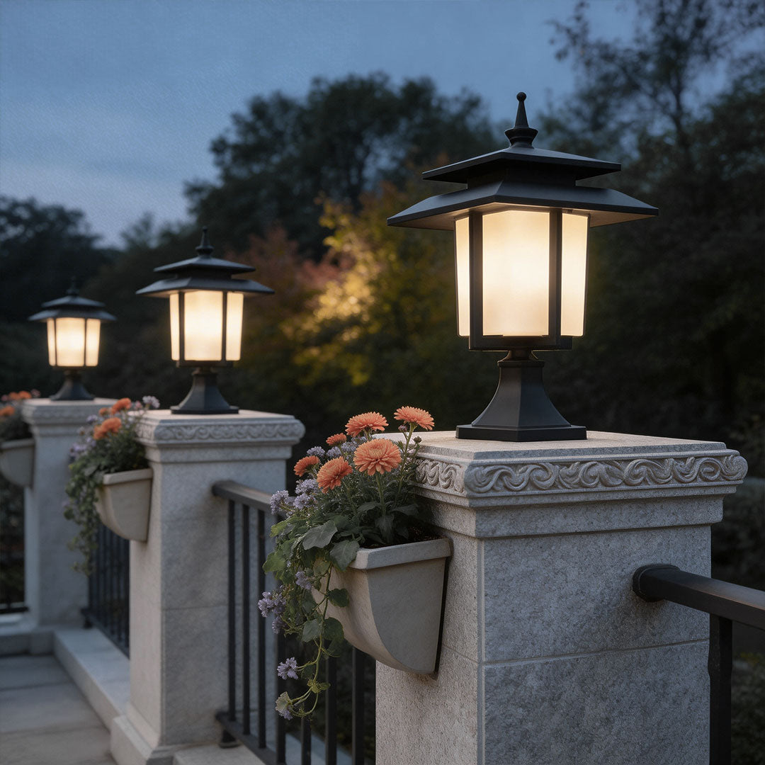 Large outdoor pillar light with classic design illuminating a flower-adorned pillar near a residential entrance.