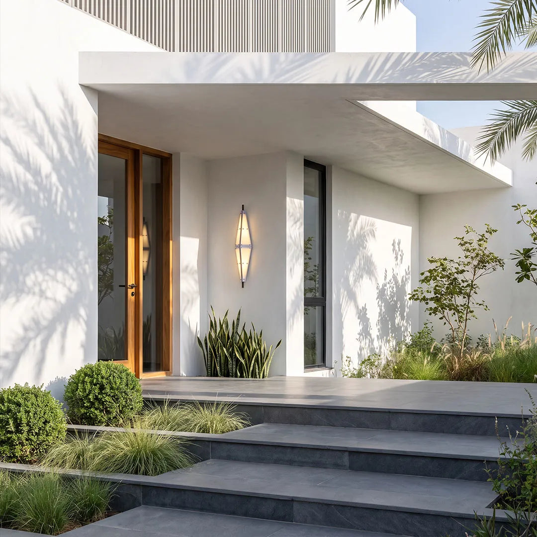 Large outdoor sconces mounted beside a contemporary front entrance with clean white walls and landscaped steps.