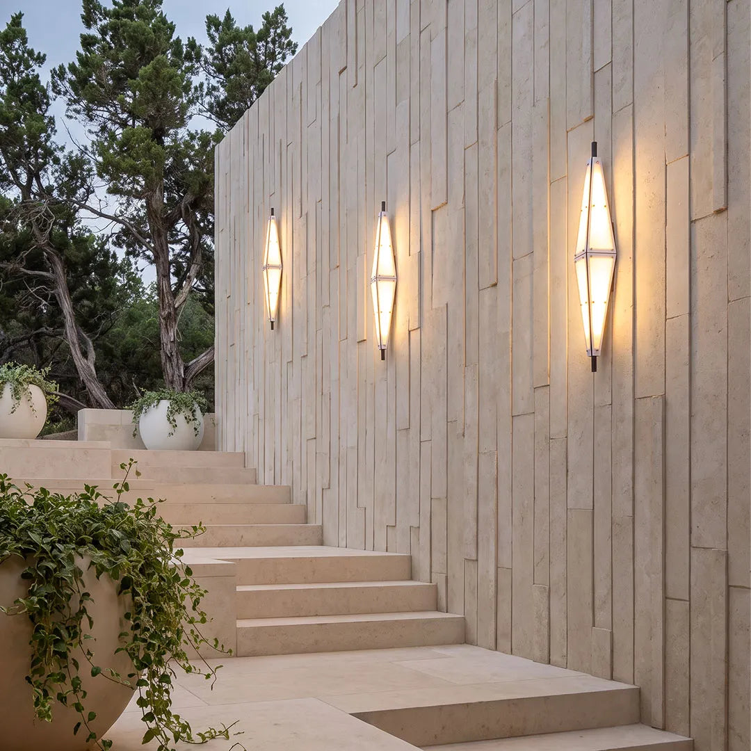 Large outdoor sconces installed along a modern stone stairway wall with a tall sculptural design.