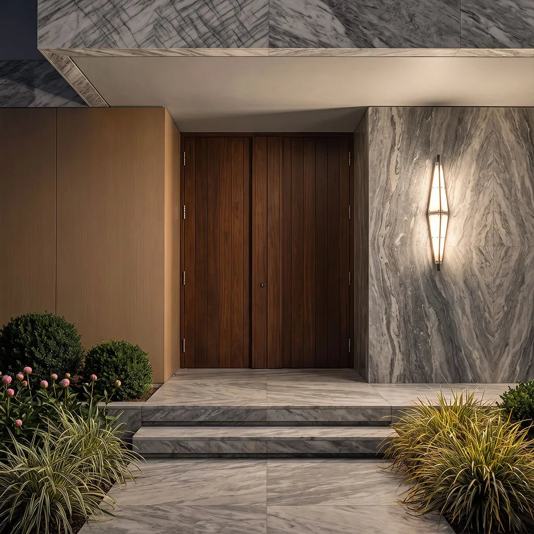 Large outdoor sconces flanking a modern wood front door on a stone-clad exterior wall.