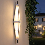 Large outdoor sconces mounted on a stucco exterior wall, featuring a tall geometric shape and warm illumination.