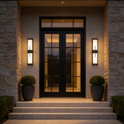 Large outdoor wall light fixture with sleek black frame, illuminating a modern house entrance.