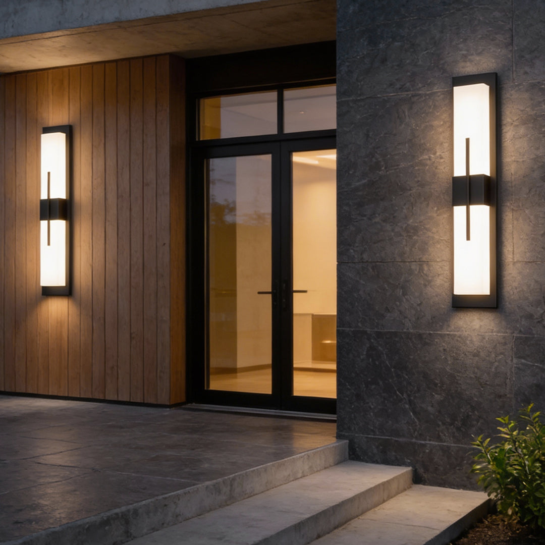 Large outdoor wall light fixtures providing warm illumination near a wooden door and stone wall.