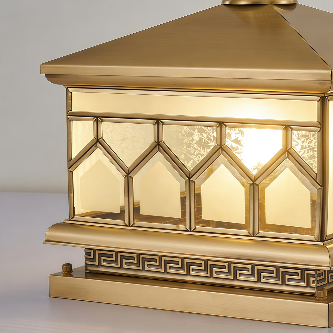 Large solar pillar lights close-up featuring geometric glass panels and decorative gold metal frame.