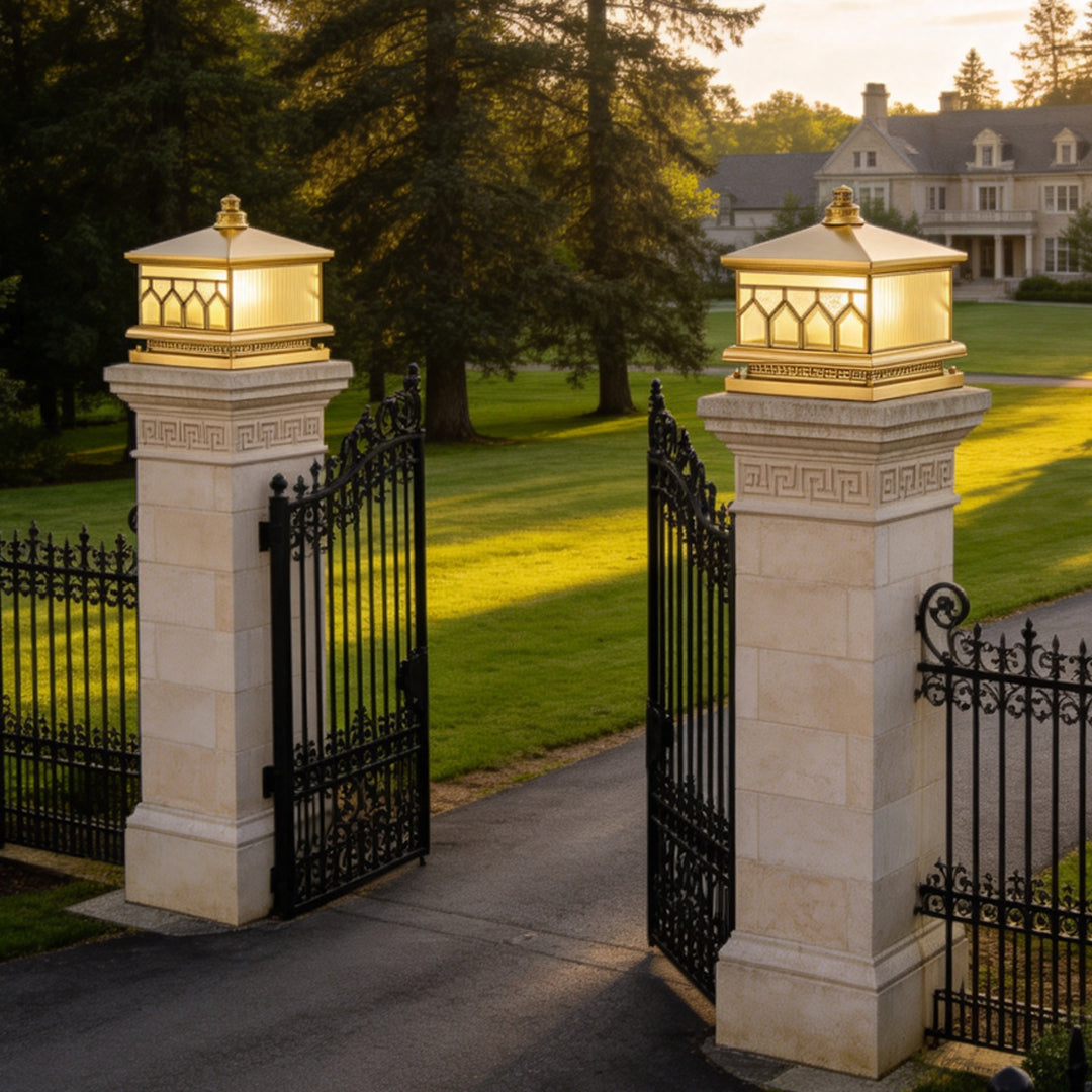 Large solar pillar lights illuminating luxury stone gate columns with warm outdoor lantern lighting.