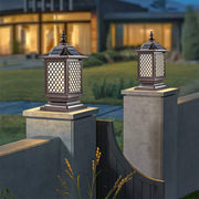 Pair of decorative post cap lights with lattice design illuminating concrete pillars at twilight