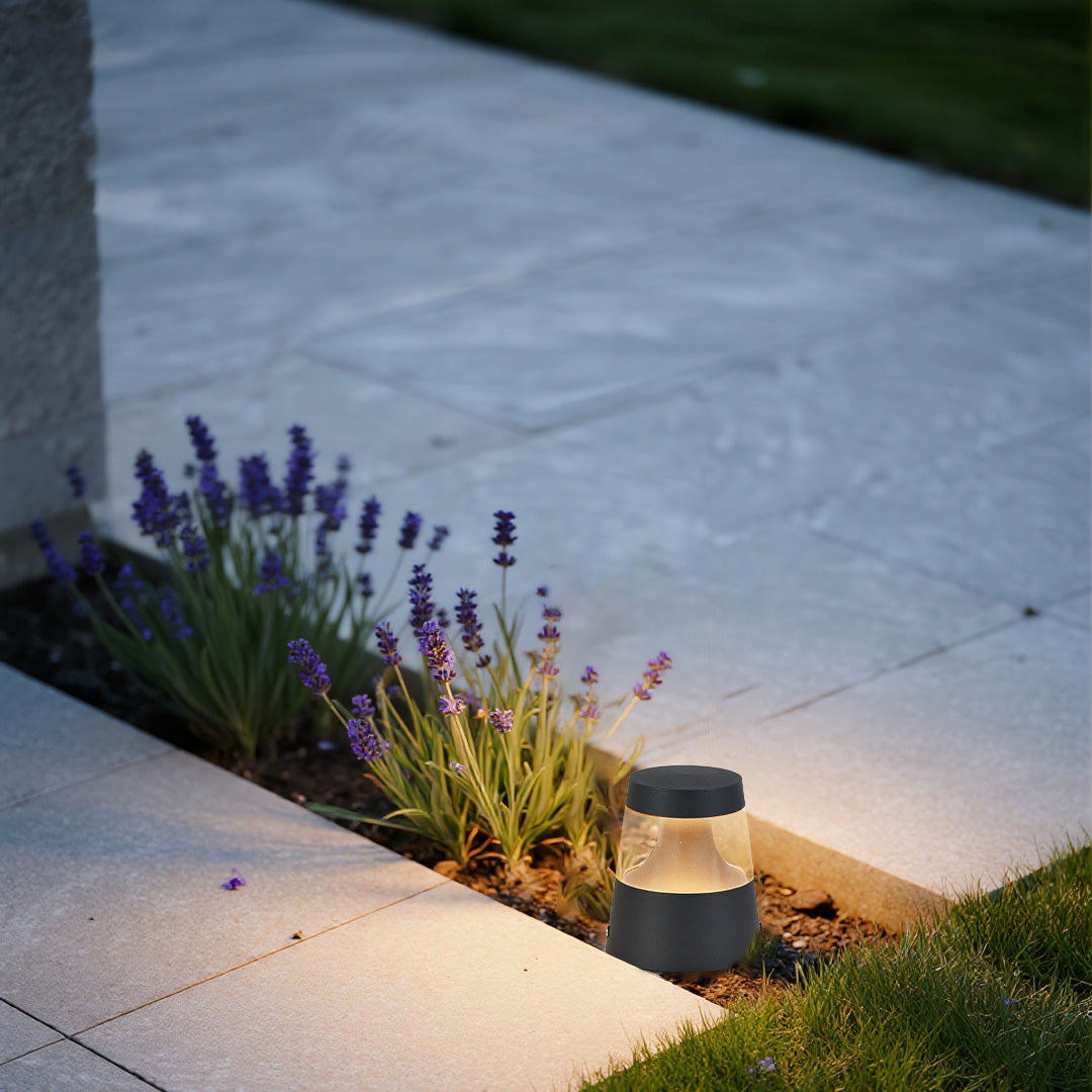 Small landscape lights providing gentle pathway illumination through lavender garden with modern concrete walkway