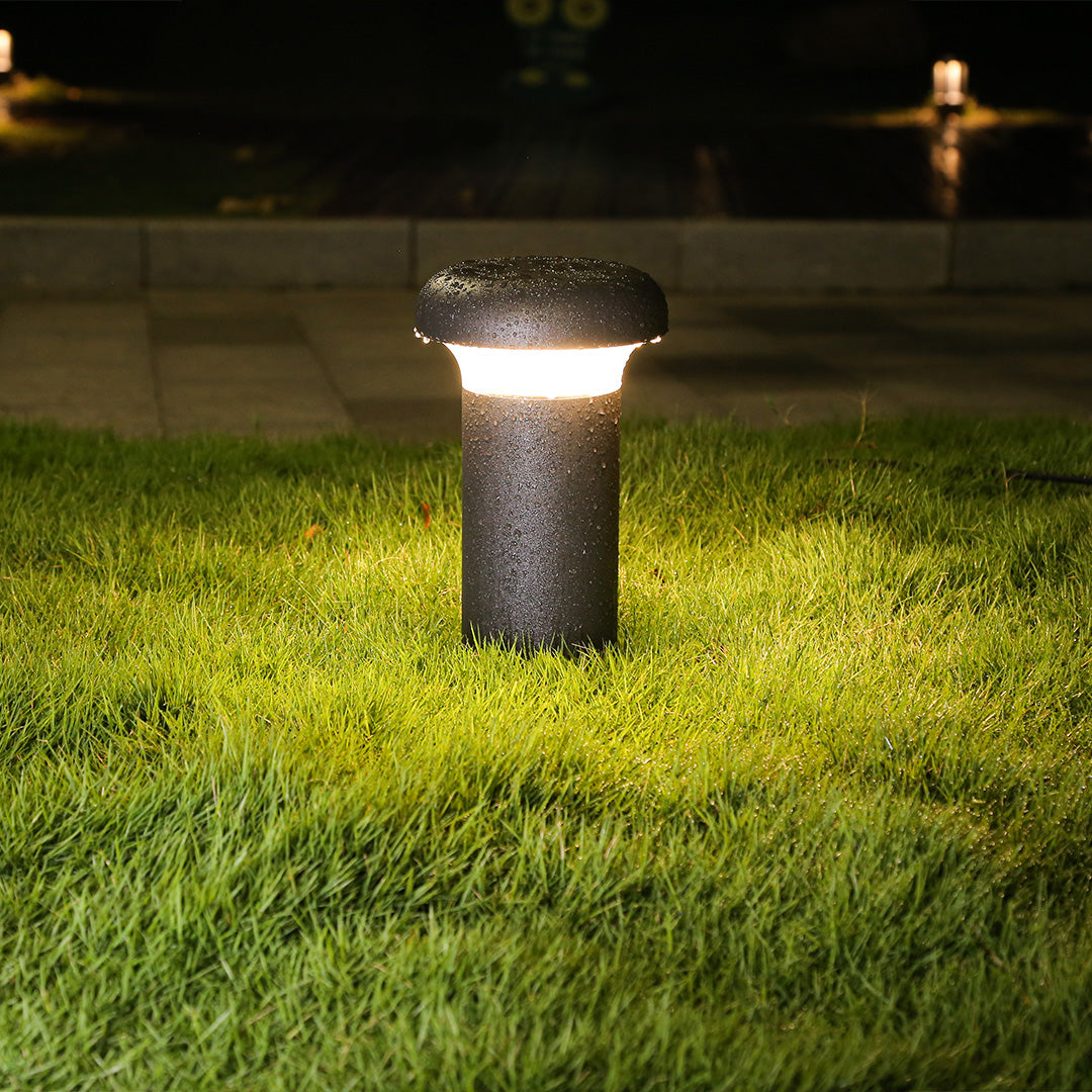 Single dark bollard light fixture standing on manicured grass area