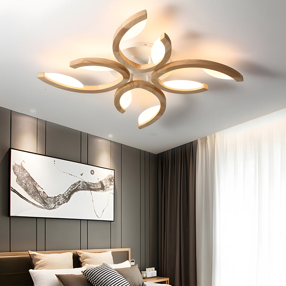 Close-up view of a contemporary leaf ceiling light with curved petal-like arms glowing warmly against a white ceiling.