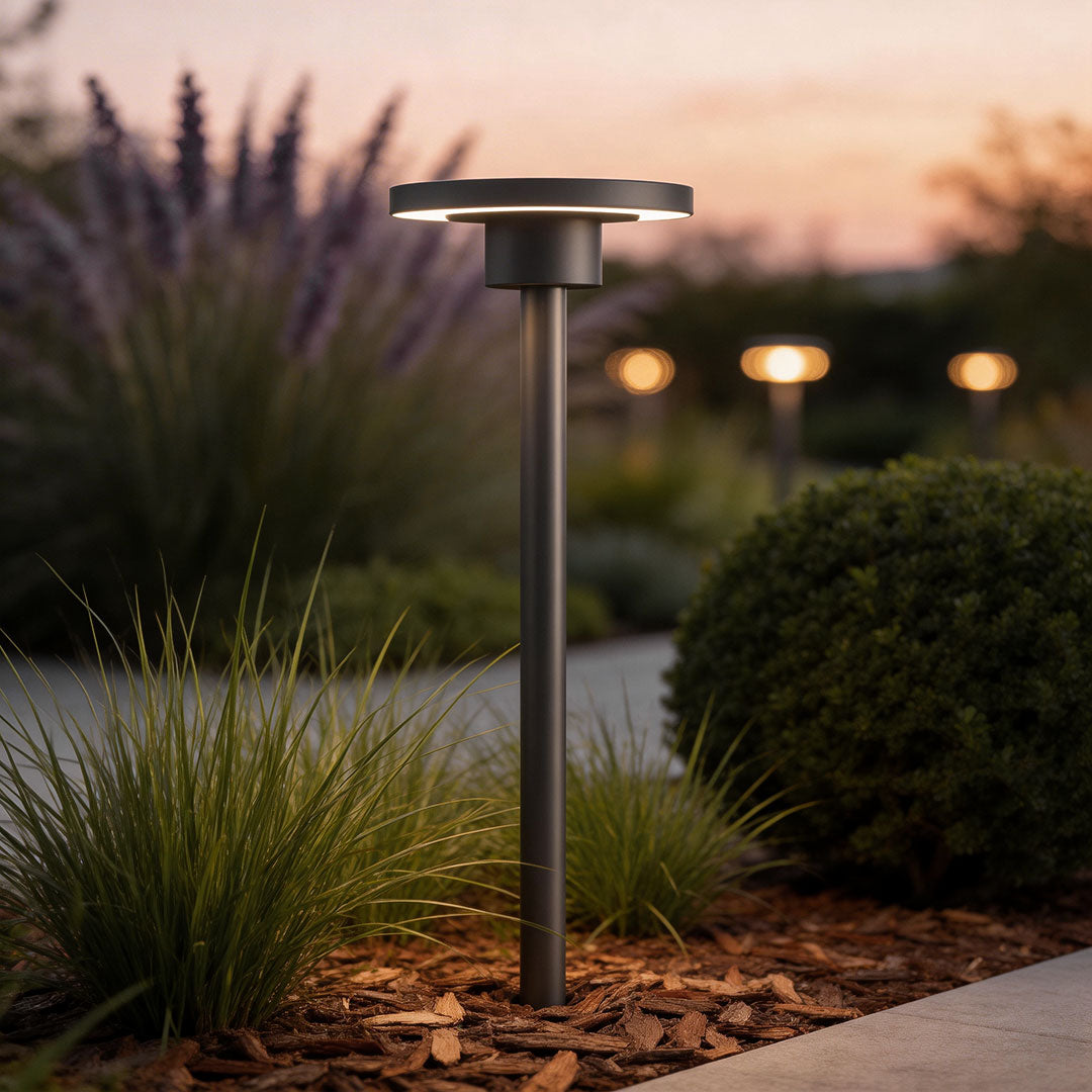 LED bollard path lights with a modern design, illuminating a garden pathway at dusk.