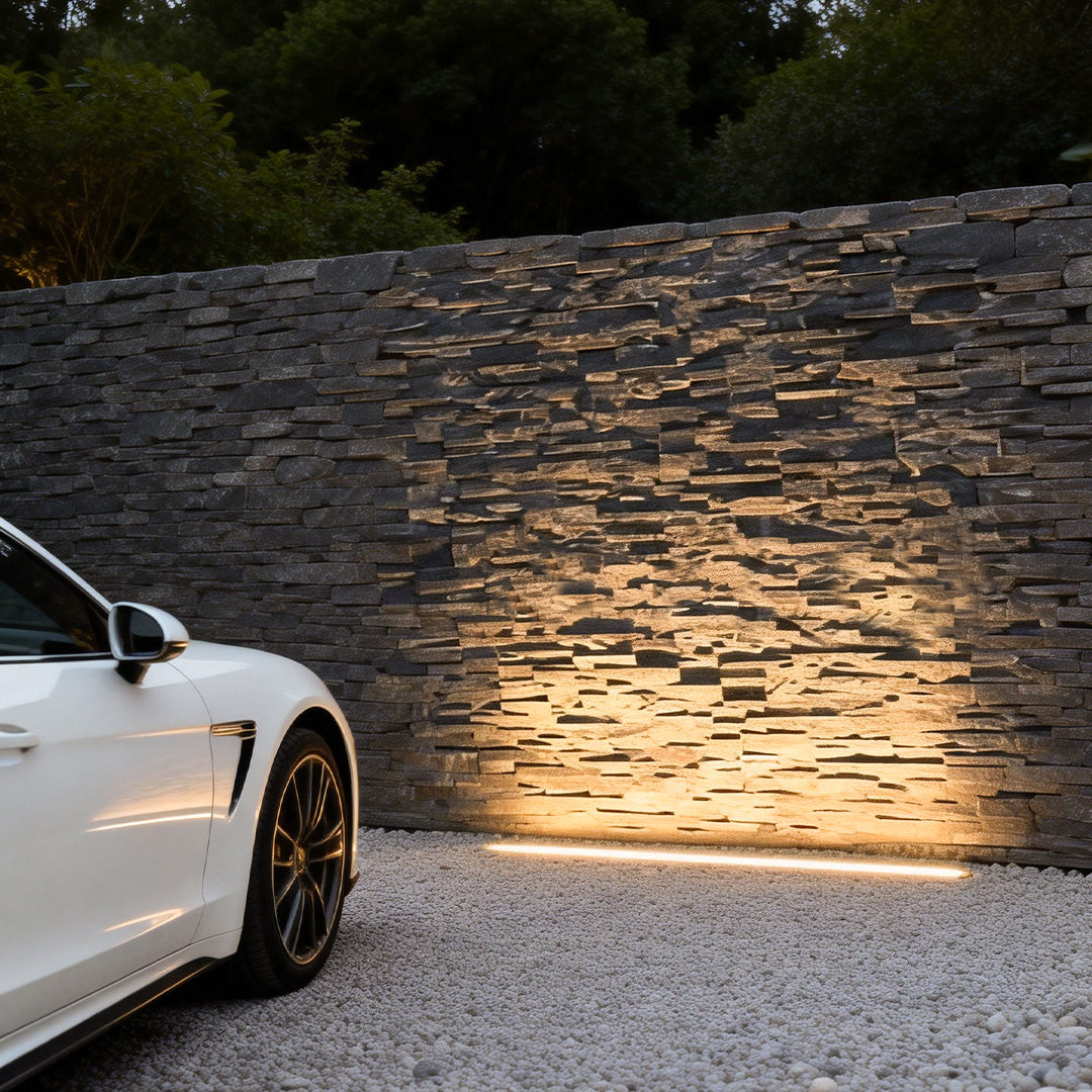 LED building facade lighting highlighting a stone wall beside a white car for elegant outdoor ambiance.