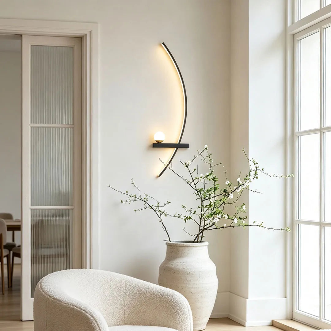 LED curved wall light mounted in a bright corner seating area with a soft warm glow and sculptural form.