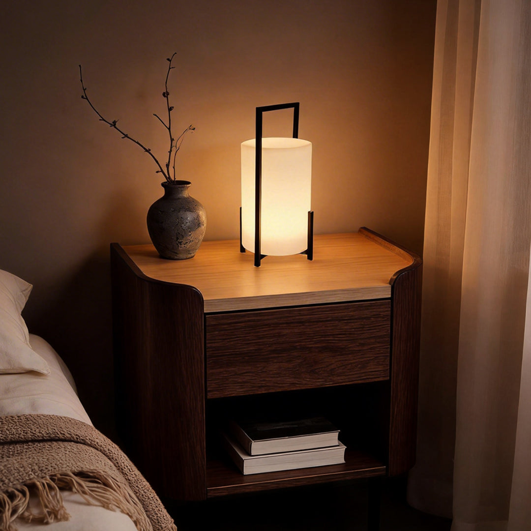 LED cylinder light fixture with a minimalist design, providing warm illumination on a bedside table.