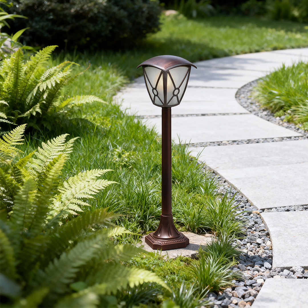 LED fence bollard light standing on green lawn beside curved concrete pathway and ferns