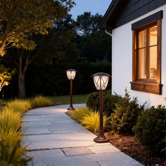 LED fence bollard light brightening stone walkway leading to white home entrance at dusk