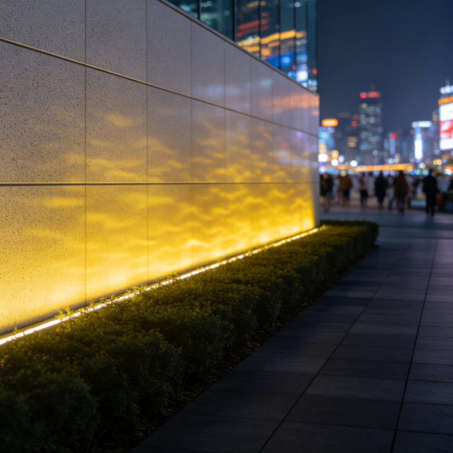 LED flood light fixtures creating warm ripple lighting effect on modern commercial building wall.