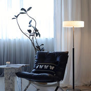 LED floor lamp positioned next to dark leather chair in contemporary room setting